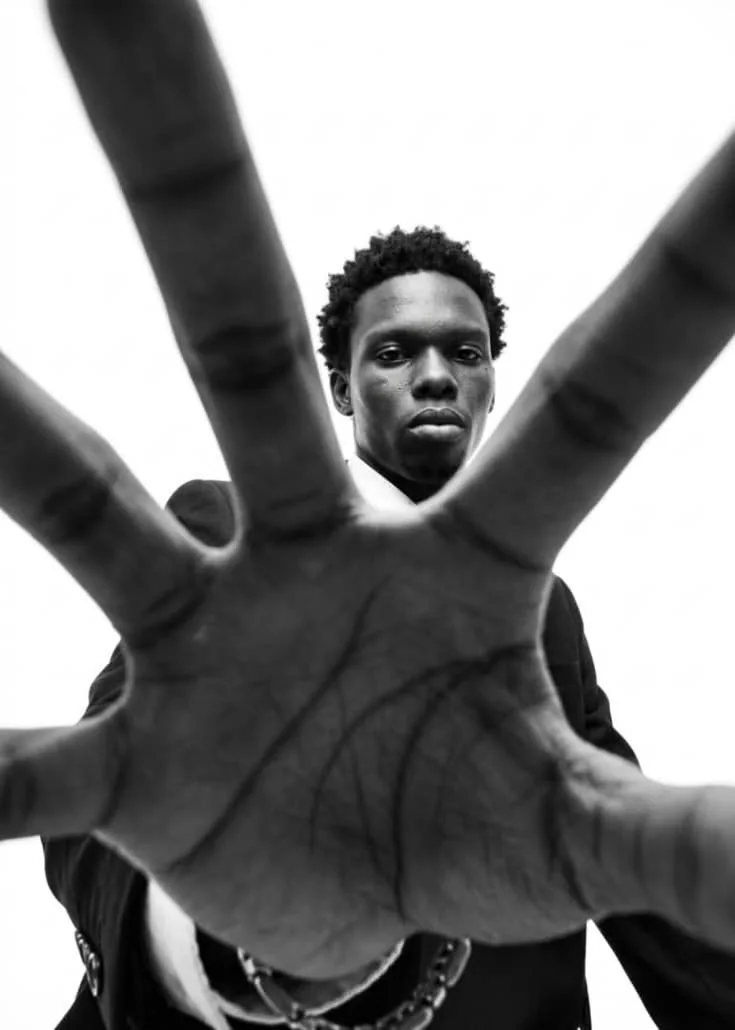 Black-and-white portrait of a man reaching an open hand toward the lens.
