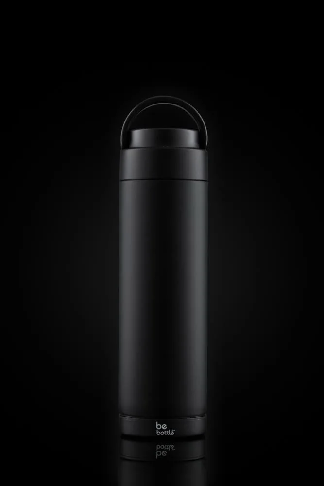 Matte black bottle lit against a pure black background with a soft reflection.